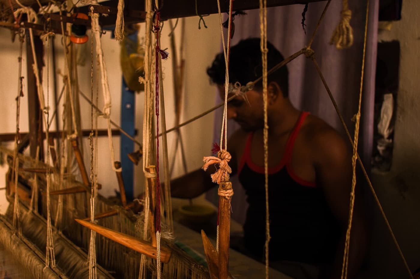 A weaver working at a wooden handloom in warm evening light